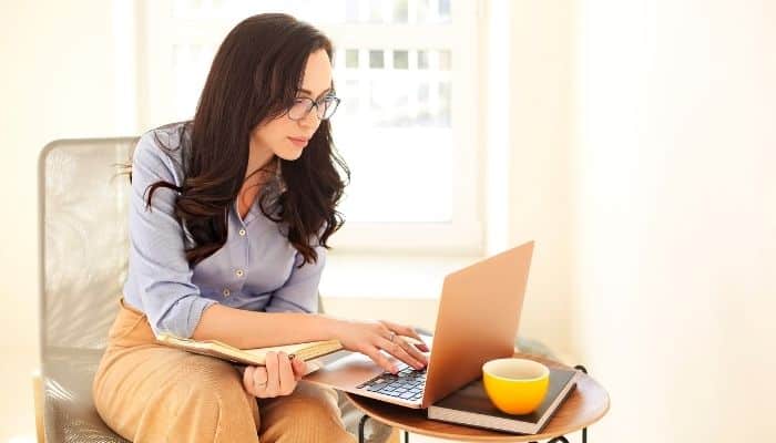 Woman sitting on a chair with her laptop in front of her as she is writing a corporate newsletter