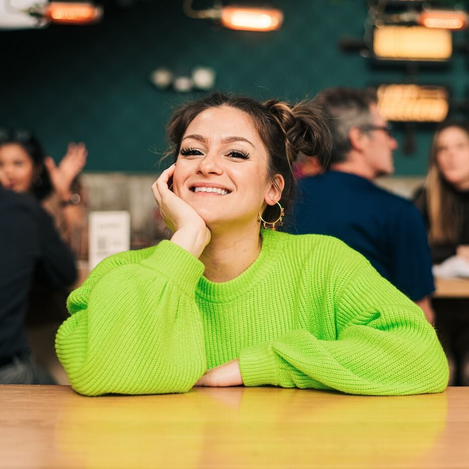 Corporate Quitter owner Gabby Ianniello wearing a bright green sweater and smiling shares her strategies to make money with email list