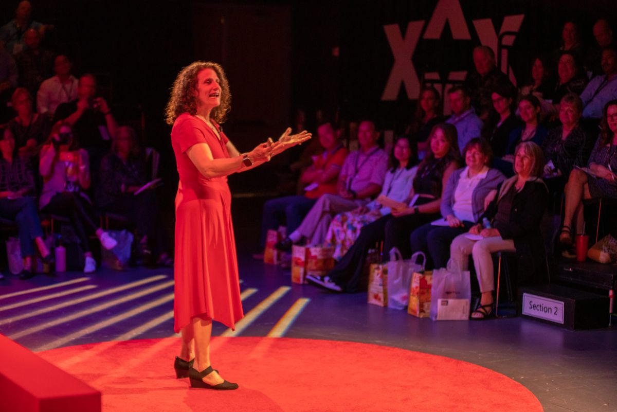 DEI trainer Meryl Evans wearing red dress while speaking at live event