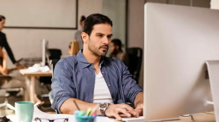 Young man seated at his computer looks for the best disposable email provider.