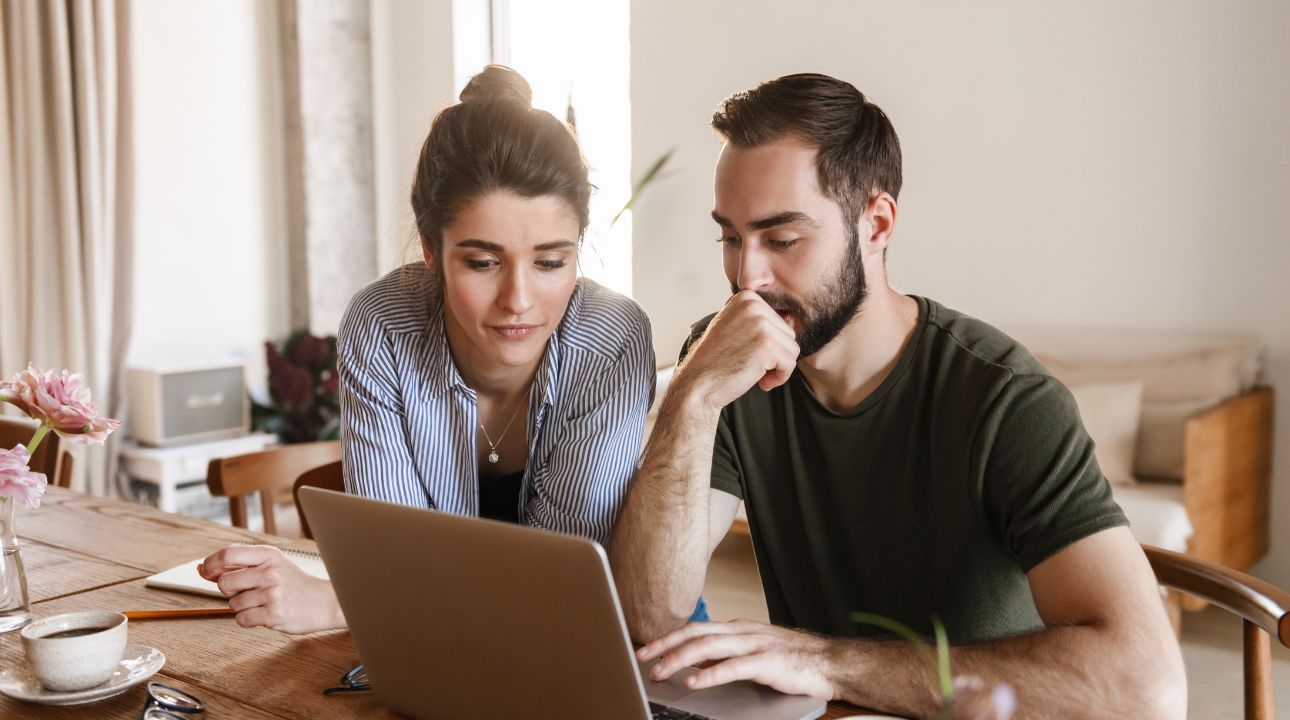 man and woman working on laptop together with coffee cup resting on table