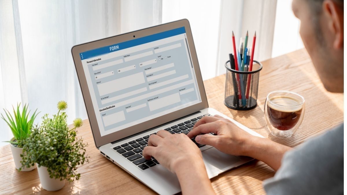Screenshot of man at laptop using a Google Form with attached email validation API. Coffee cup is nearby.