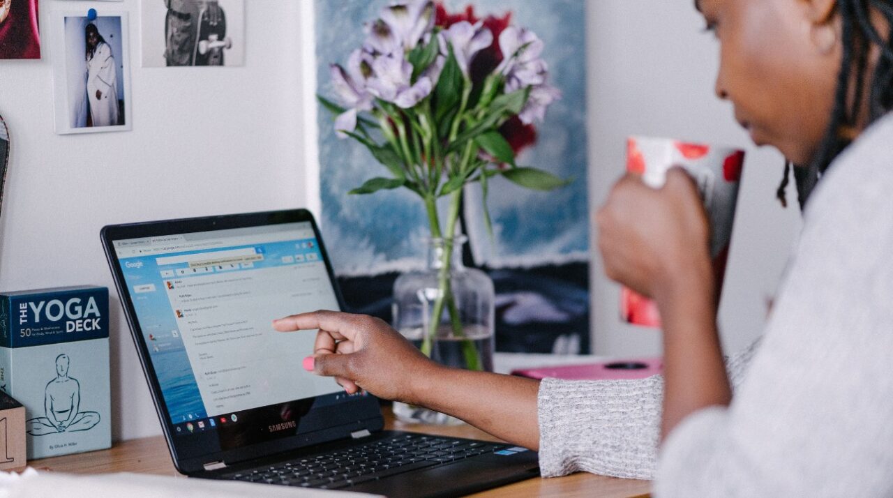 Picture of young woman drinking coffee and pointing to a laptop screen showing an email to illustrate ZeroBounce article on B2B email marketing