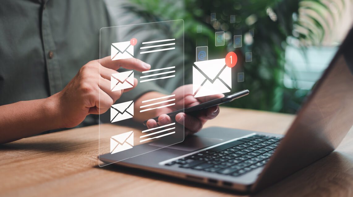 Man's hands shown while working on laptop with email elements illustrating how managers and employees use AI to write emails and layoff emails