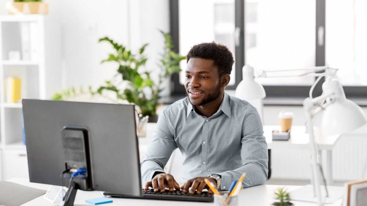Young man sits before a computer getting a handle on email verification to ensure compliance.